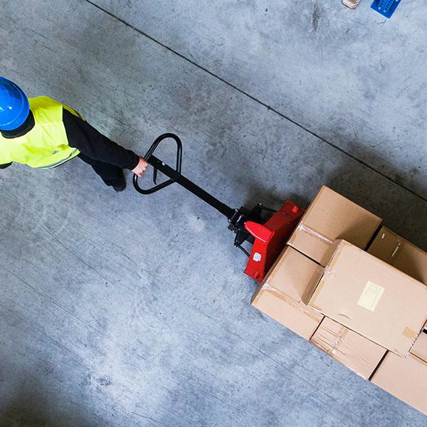 Man pulling pallet truck through warehouse