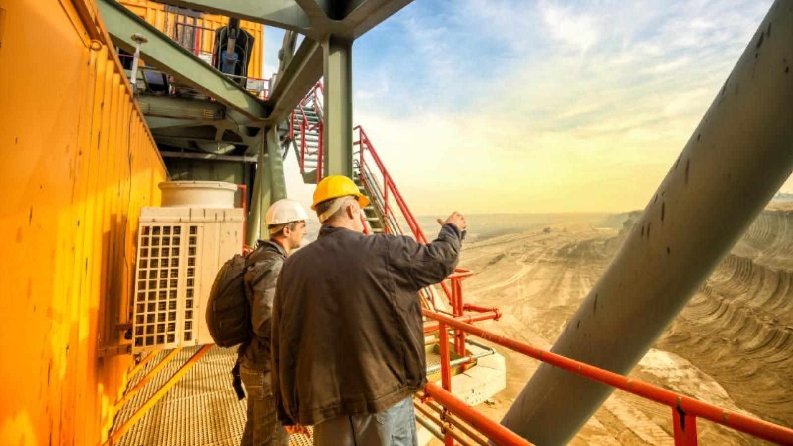 Two men looking over a mining plant, dusty and low light.